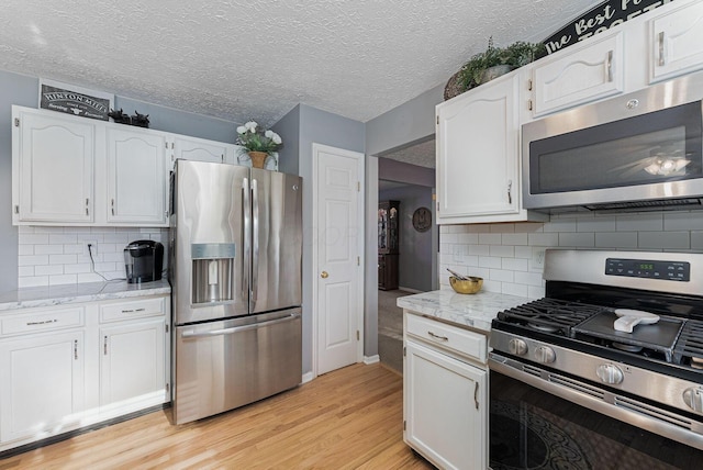 kitchen with stainless steel appliances, light wood-style floors, and white cabinetry