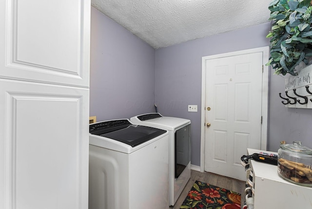 clothes washing area with washer and clothes dryer, laundry area, wood finished floors, baseboards, and a textured ceiling