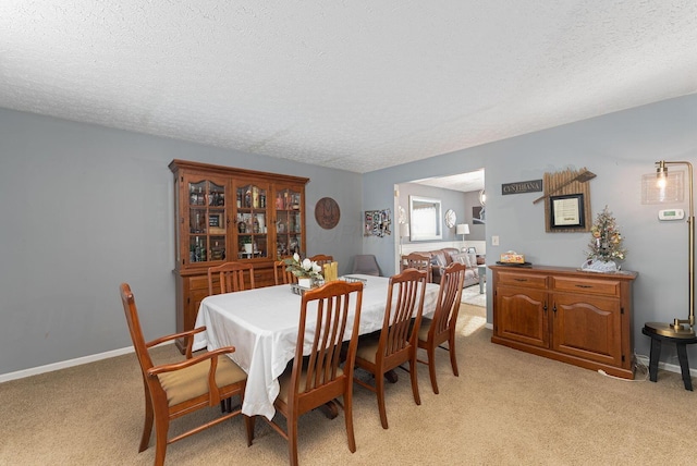 dining area featuring light carpet and a textured ceiling