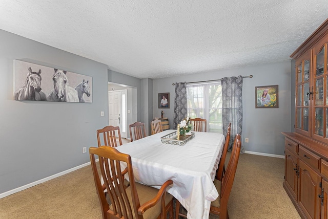 dining space with baseboards, a textured ceiling, and light colored carpet