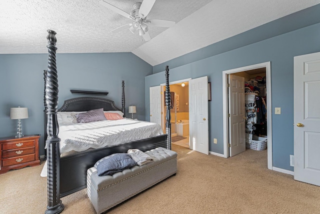 carpeted bedroom featuring a textured ceiling, baseboards, lofted ceiling, connected bathroom, and a walk in closet