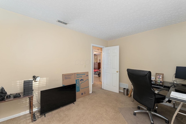 home office with carpet flooring, a textured ceiling, and visible vents