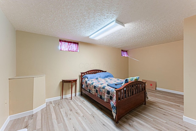 bedroom with baseboards, wood finished floors, and a textured ceiling