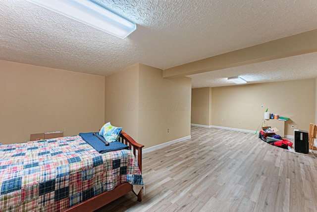 bedroom with baseboards, wood finished floors, and a textured ceiling
