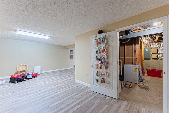 finished below grade area featuring baseboards, wood finished floors, a textured ceiling, and electric panel