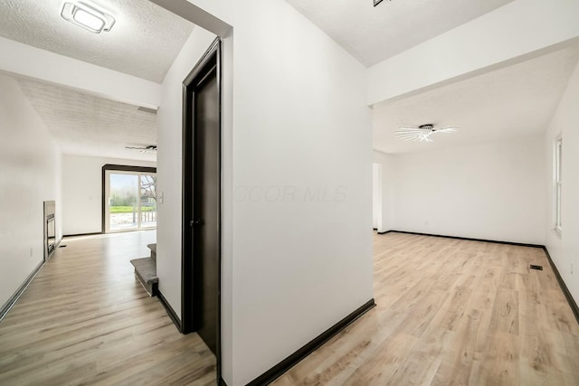 hall with stairs, visible vents, a textured ceiling, and light wood-style floors