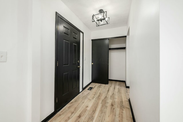 hallway with light wood-style floors and visible vents