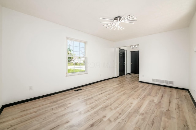 spare room featuring wood finished floors, visible vents, and baseboards
