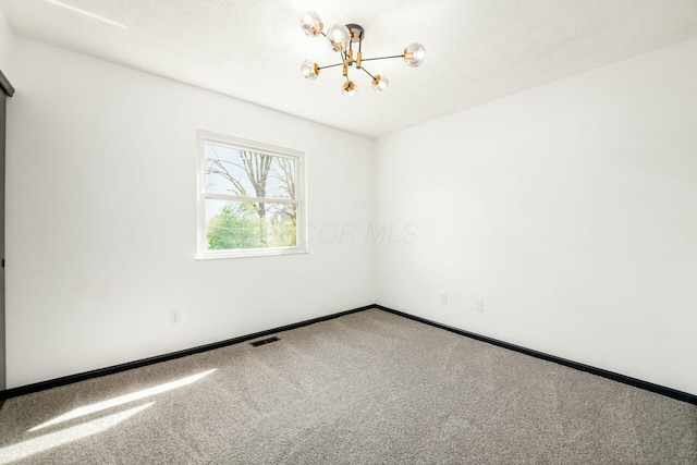 carpeted spare room featuring an inviting chandelier, visible vents, and baseboards