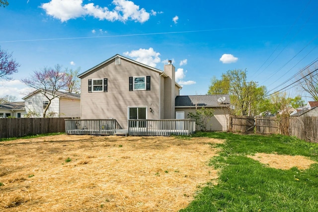 back of house featuring a chimney, a yard, a wooden deck, and a fenced backyard
