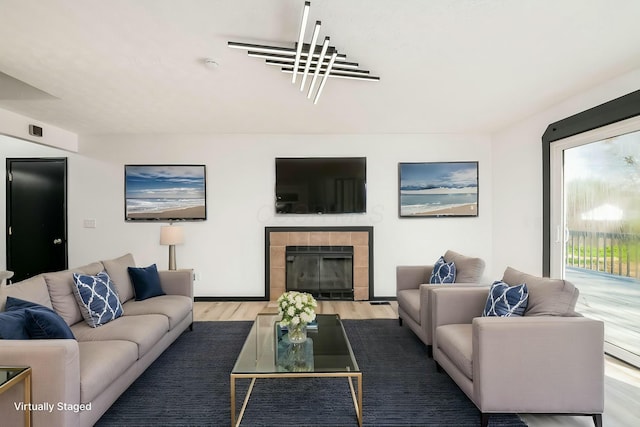 living room featuring a tiled fireplace and wood finished floors