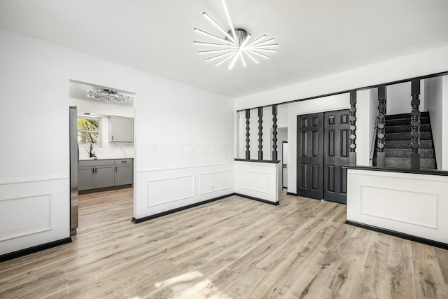 entrance foyer featuring wainscoting, light wood finished floors, and a decorative wall
