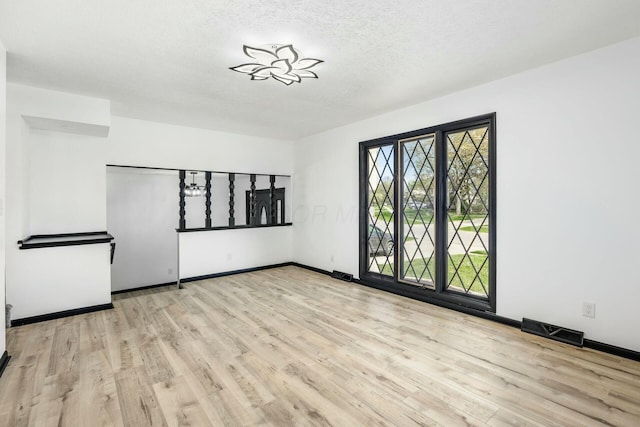 unfurnished room featuring baseboards, visible vents, and wood finished floors