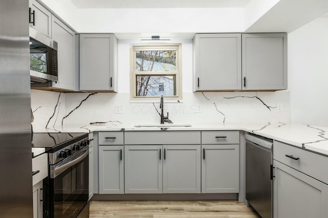 kitchen with gray cabinetry, a sink, appliances with stainless steel finishes, and a wealth of natural light