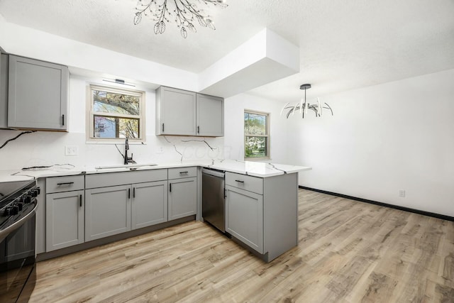 kitchen featuring gray cabinets, stainless steel dishwasher, a notable chandelier, and a sink