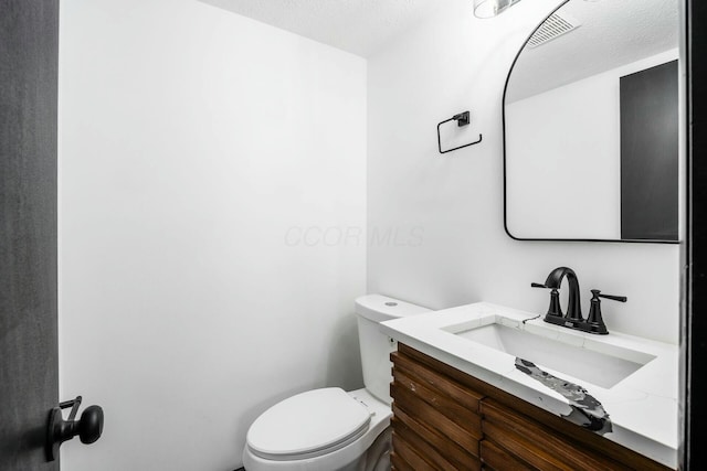 half bathroom featuring visible vents, toilet, and vanity