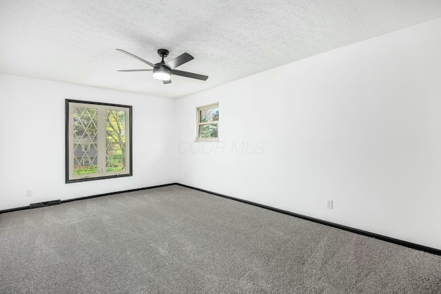 empty room with a textured ceiling, ceiling fan, carpet flooring, and baseboards
