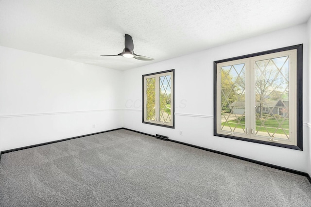 carpeted spare room with visible vents, ceiling fan, a textured ceiling, and baseboards