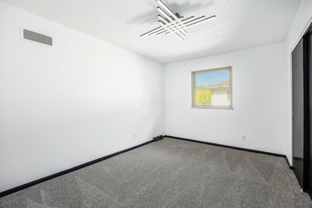 unfurnished room featuring carpet flooring, a textured ceiling, visible vents, and baseboards