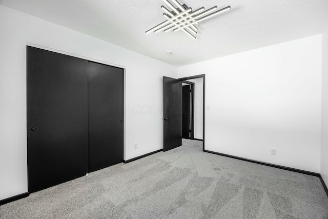 unfurnished bedroom with baseboards, a closet, and light colored carpet