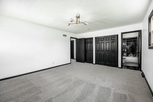 unfurnished bedroom featuring carpet flooring, a notable chandelier, multiple closets, and visible vents