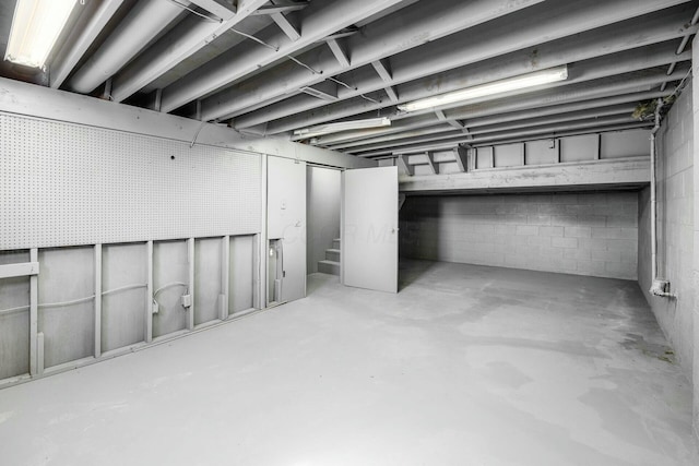 basement with concrete block wall and stairs