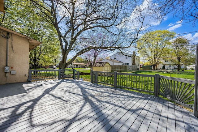 deck with a residential view, an outbuilding, a yard, a shed, and fence