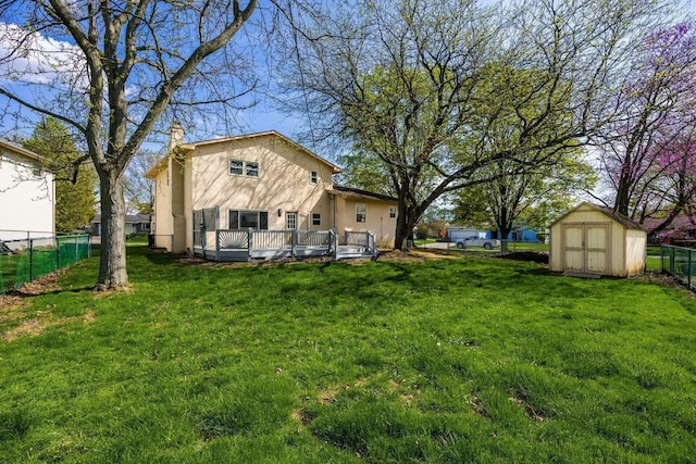 back of property featuring a wooden deck, a shed, a lawn, stucco siding, and fence
