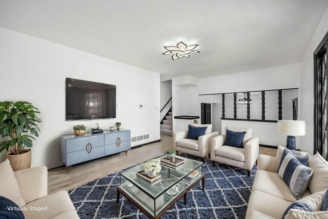 living room featuring visible vents, stairway, and wood finished floors