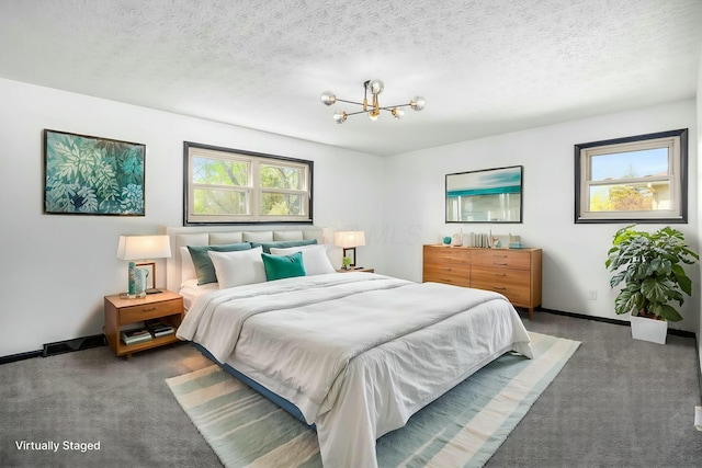 carpeted bedroom with a textured ceiling, a notable chandelier, and baseboards