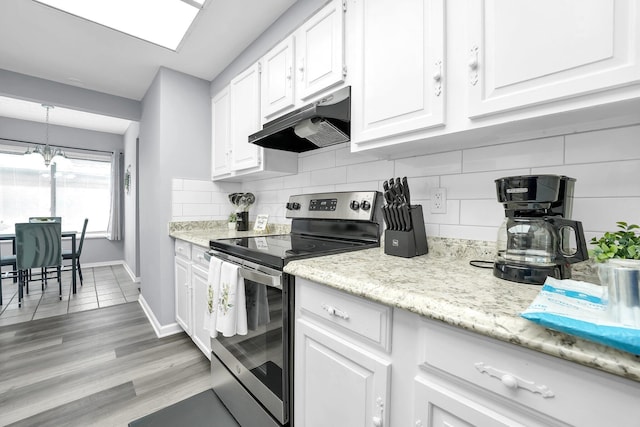 3236 Donalda Ct, Columbus, OH 43231 - kitchen with stainless steel electric stove, under cabinet range hood, a chandelier, white cabinets, and decorative backsplash