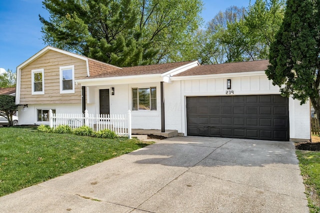 tri-level home with fence, a shingled roof, a garage, driveway, and a front yard