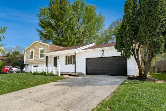 split level home featuring concrete driveway, board and batten siding, an attached garage, fence, and a front lawn