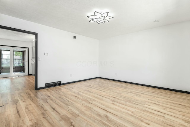 unfurnished room featuring visible vents, light wood-style flooring, and baseboards