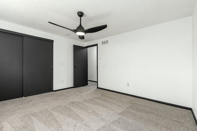 unfurnished bedroom with light colored carpet, a closet, ceiling fan, baseboards, and visible vents
