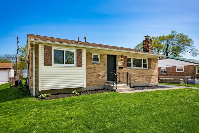 ranch-style home featuring fence, a chimney, a front yard, and brick siding