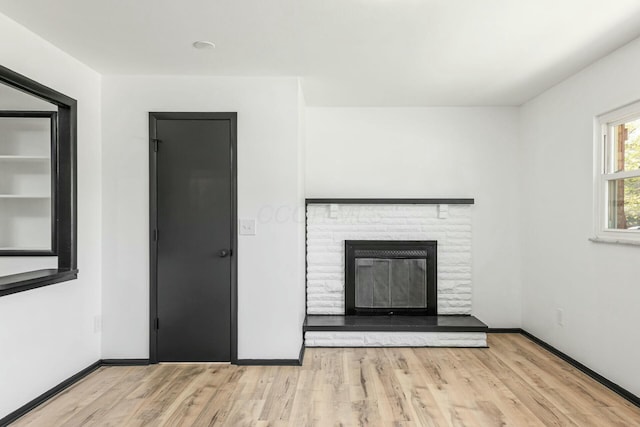 unfurnished living room with a fireplace, wood finished floors, and baseboards
