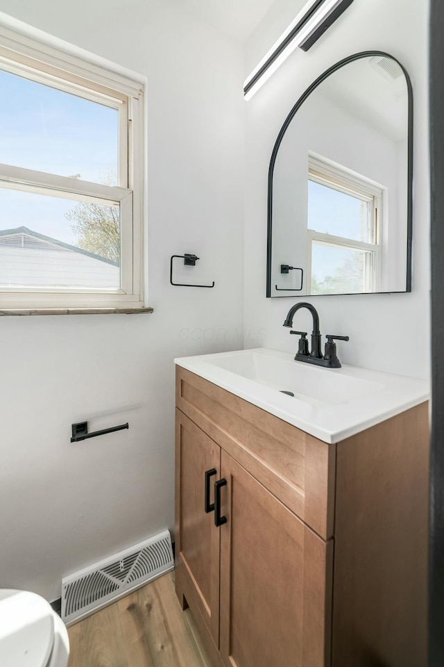 half bathroom featuring visible vents, wood finished floors, and vanity