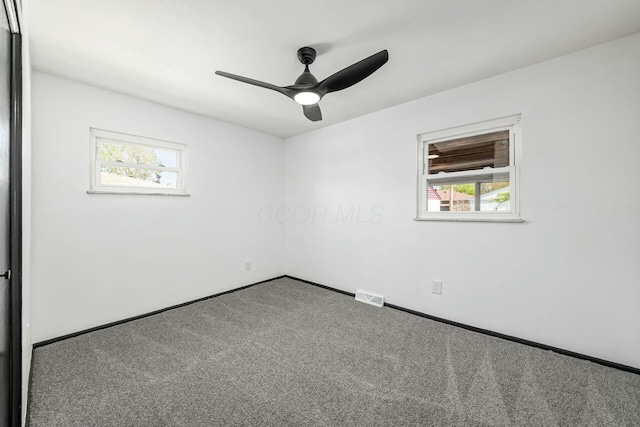 carpeted empty room featuring visible vents, ceiling fan, and baseboards