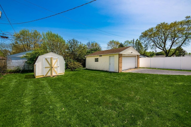 view of yard featuring an outdoor structure, a detached garage, aphalt driveway, and fence