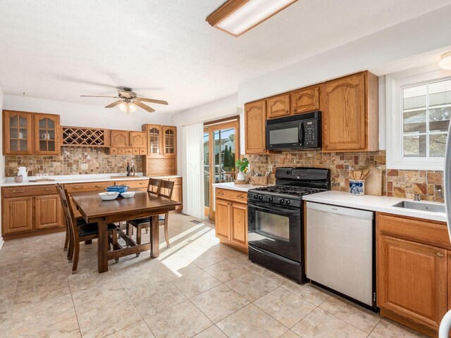 kitchen featuring tasteful backsplash, a healthy amount of sunlight, glass insert cabinets, and black appliances