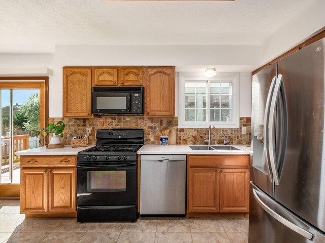 kitchen featuring a sink, brown cabinetry, black appliances, light countertops, and backsplash