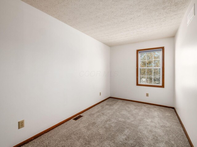 carpeted spare room with baseboards, a textured ceiling, and visible vents