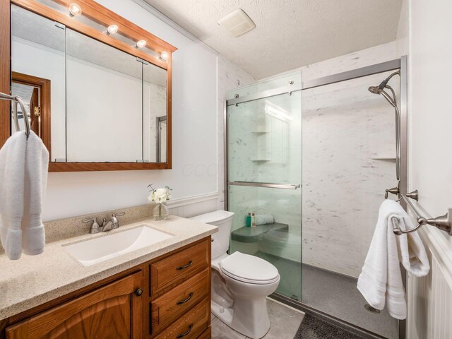 full bath with a textured ceiling, toilet, a stall shower, and vanity