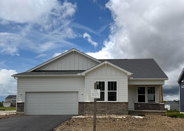 9417 Coach Line Ave Lot 118, Plain City, OH 43064 - view of front facade with driveway, board and batten siding, a porch, roof with shingles, and brick siding