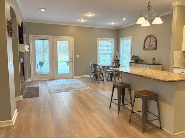 33 Hampden Dr, Granville, OH 43023 - kitchen with baseboards, a kitchen breakfast bar, light wood-type flooring, arched walkways, and pendant lighting