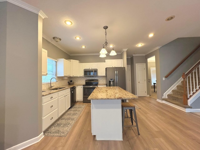33 Hampden Dr, Granville, OH 43023 - kitchen featuring appliances with stainless steel finishes, a sink, crown molding, light wood-style flooring, and light stone countertops