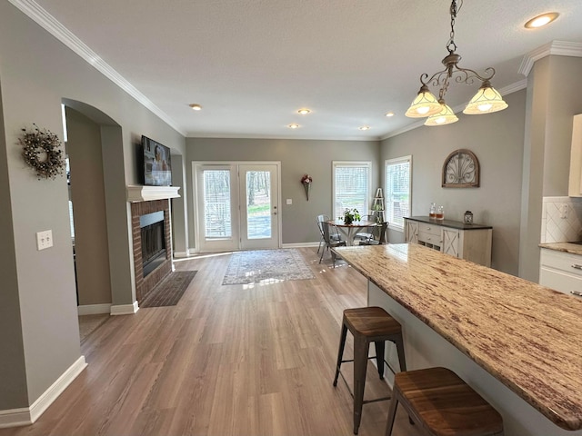 33 Hampden Dr, Granville, OH 43023 - kitchen with a breakfast bar, baseboards, crown molding, light wood-style flooring, and arched walkways