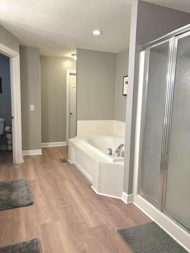 33 Hampden Dr, Granville, OH 43023 - bathroom featuring a garden tub, wood finished floors, a stall shower, a textured ceiling, and baseboards