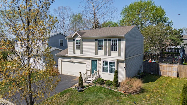 traditional home featuring fence, an attached garage, a shingled roof, a front yard, and aphalt driveway